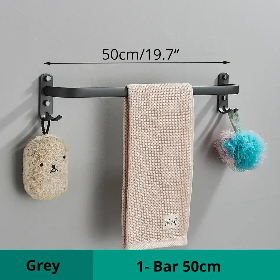 Grey aluminum bathroom towel rack with two hooks holding a beige textured towel and decorative bath accessories