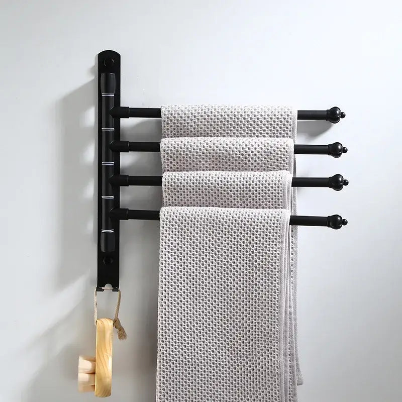 Black aluminum towel rack with four bars holding light gray towels from DecorBites bathroom hardware set