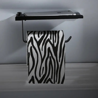 Black metal aluminum DecorBites™ wall-mounted toilet paper rack stand with integrated shelf holding a silver tablet