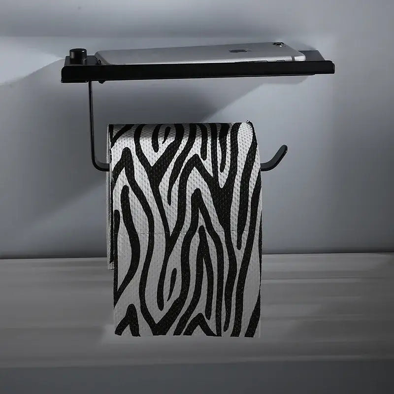 Black metal aluminum DecorBites™ wall-mounted toilet paper rack stand with integrated shelf holding a silver tablet