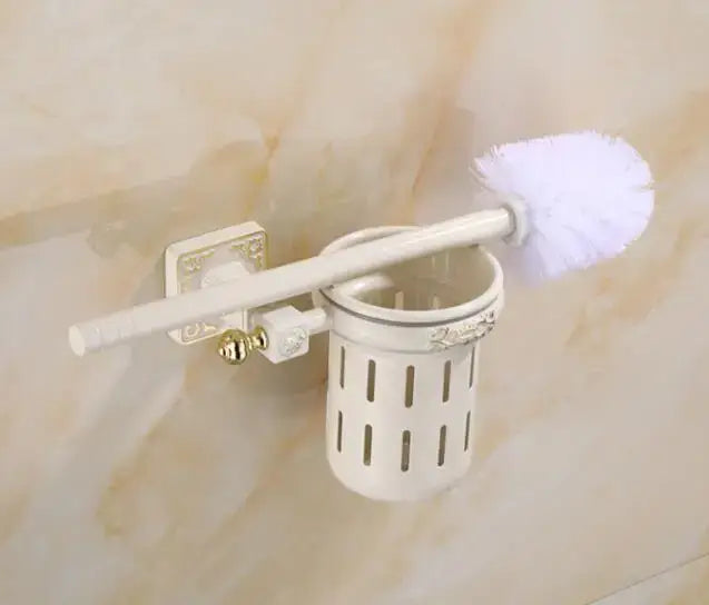 Decorbites aluminum carved toilet brush holder set features a white plastic toilet brush holder with gold-tone accents and matching brush