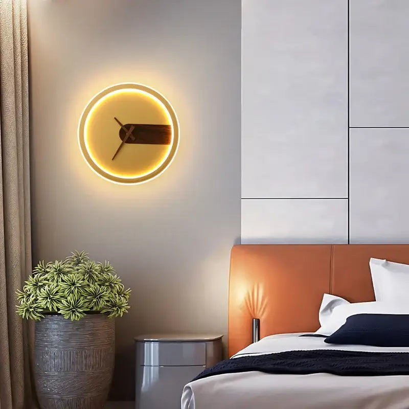 Decorbites aluminum clock wall lamp with warm yellow backlight and dark brown minimalist hands in modern led sconce design
