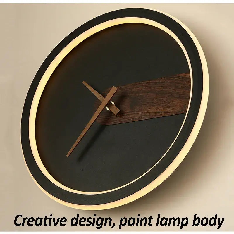 Modern aluminum clock wall lamp with sleek black face, warm ambient lighting ring, and dark wood accent strip for home use
