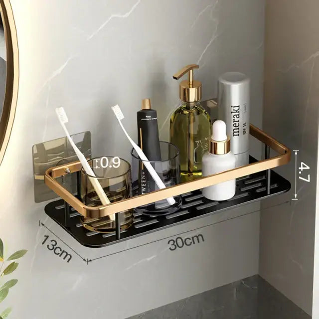 Decorbites™ aluminum corner bathroom shelf with gold-toned metal frame and black slatted base holding toiletries and toothbrushes