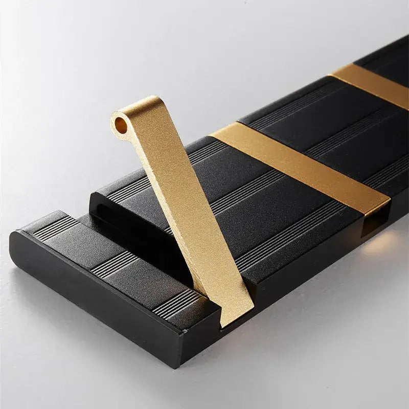Black and gold metallic aluminum folding robe hook with textured ridged panels for wall mounting and towel hanging