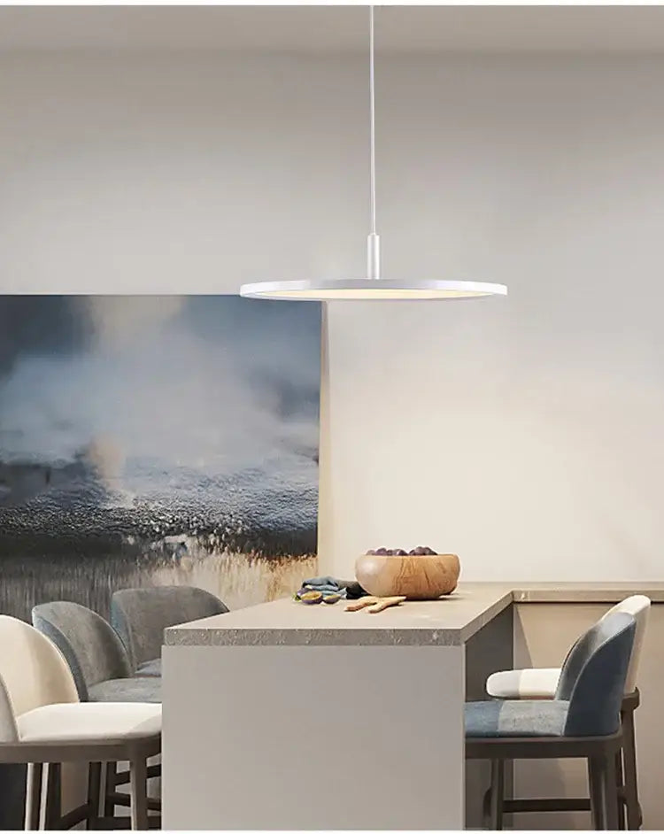 A sleek white decorbites aluminum pendant light with thin cord and circular disc design above dining area