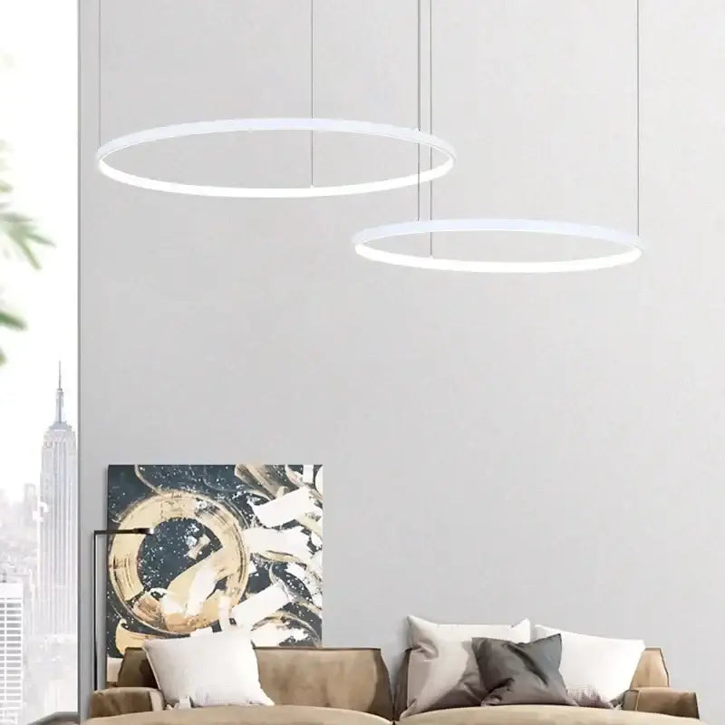 Two minimalist white aluminum rings led pendant lights hang from the ceiling in living room and bedroom settings