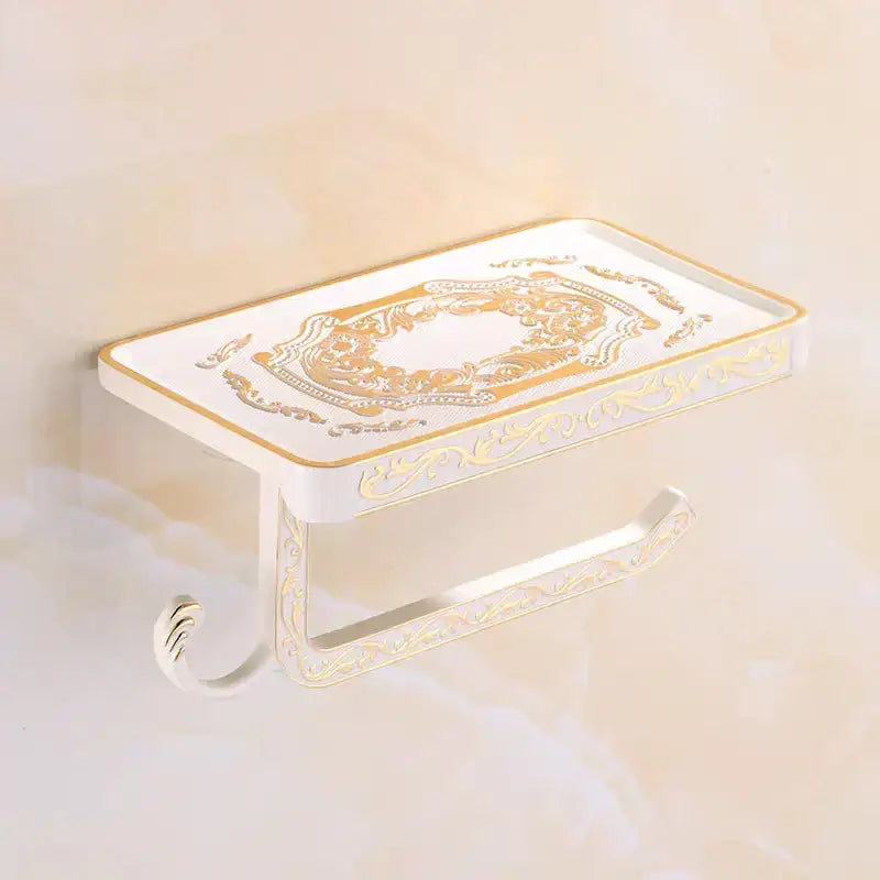 White and gold ornate aluminum toilet paper holder by DecorBites with decorative scrollwork and phone rack hook