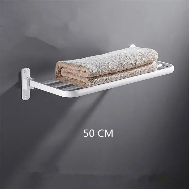 White metal wall-mounted decorbites aluminum towel rack holding two folded beige towels in a bathroom setting