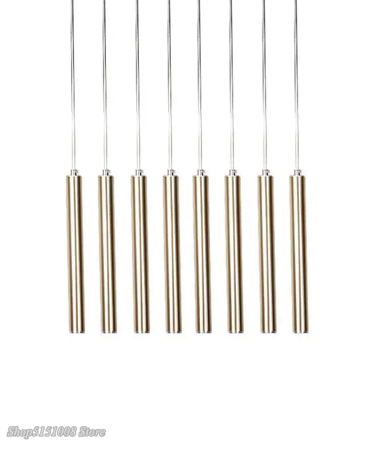 Set of seven sleek cylindrical brass decorbites pendant light fixtures with slender metallic rods for kitchen and dining room