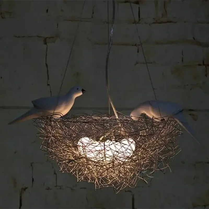 A DecorBites aluminum wire bird’s nest pendant light with white ceramic birds and an illuminated heart-shaped bulb