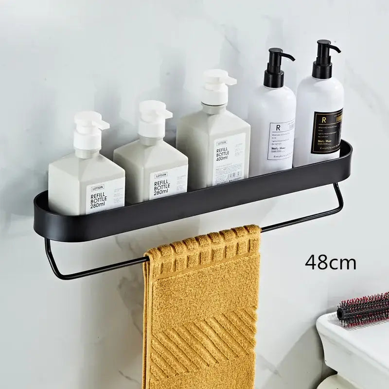 DecorBites™ black aluminum bathroom shelf with towel bar and corner storage shelf holding white pump bottles and towel