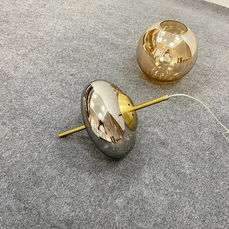 Two spherical glass lampshades with amber glass and reflective silver finish on gold stems for amber glass chandelier