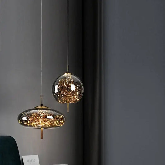 Two modern pendant lights of the decorbites™ amber glass chandelier with clear amber glass globes and golden fairy lights