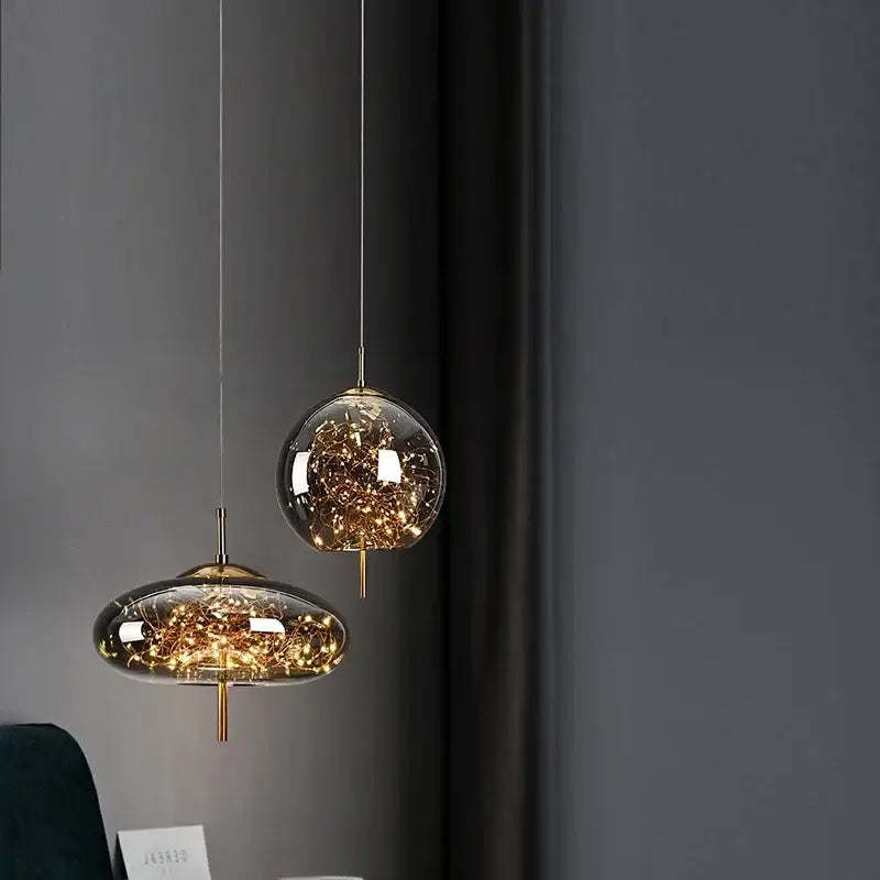 Two modern pendant lights of the decorbites™ amber glass chandelier with clear amber glass globes and golden fairy lights