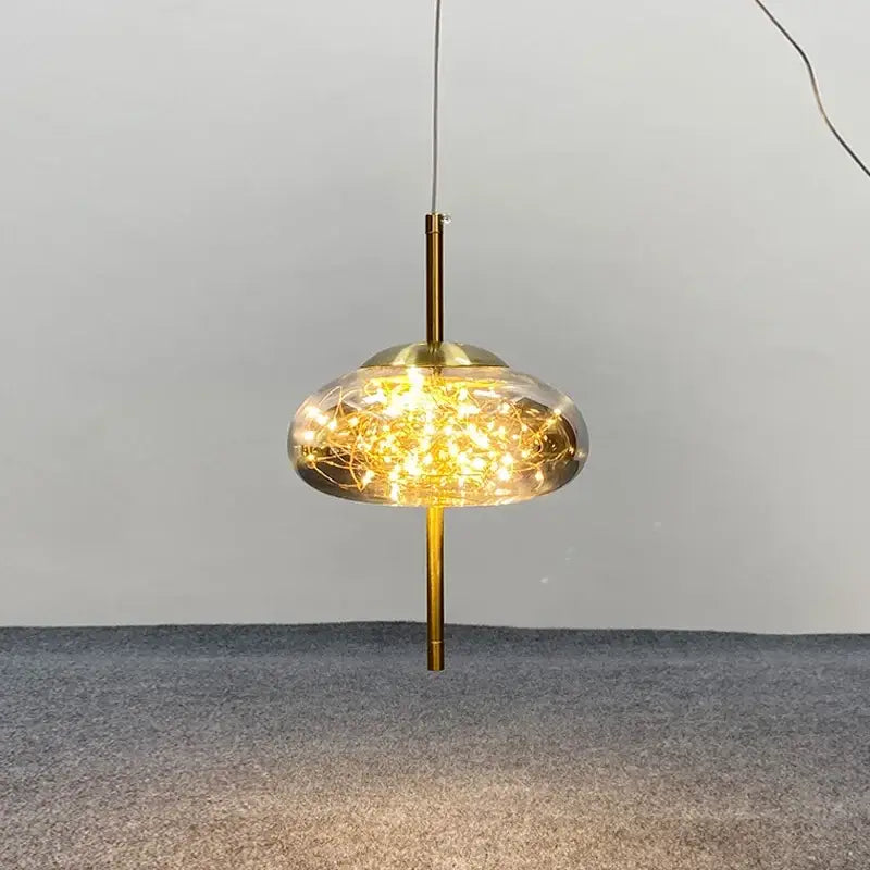 Decorbites amber glass chandelier featuring a gold-toned pendant light with clear glass dome and warm string lights