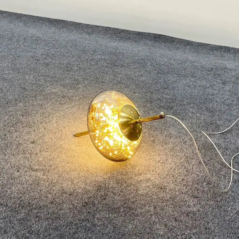 A warm amber glass chandelier featuring a glowing globe lamp with brass base for luxury pendant lighting