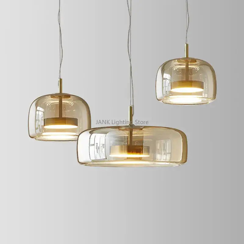 Three modern decorbites amber glass chandelier pendant lights with warm amber glass shades and brass accents hanging from cords