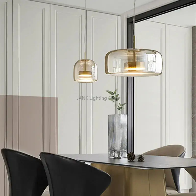 Two DecorBites amber glass chandelier pendant lights with smoked glass and gold fixtures hang above a dining table