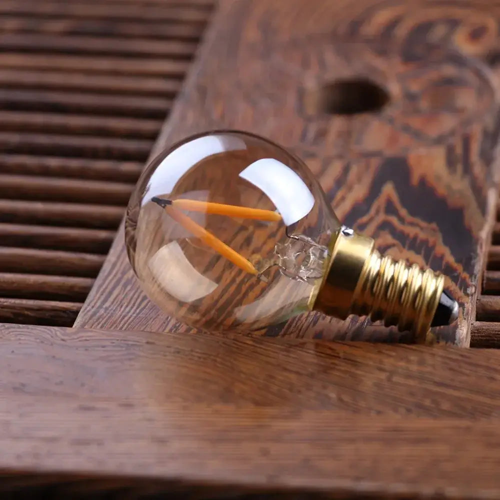 Clear glass globe bulb with two orange led filaments and brass e14 screw base for amber glass led lighting