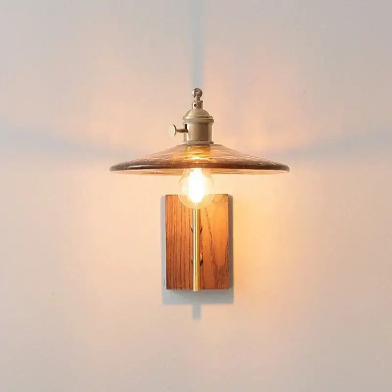 Warm-toned brass wall lamp with decorbites amber glass led smoked glass shade and wooden backing for modern decor