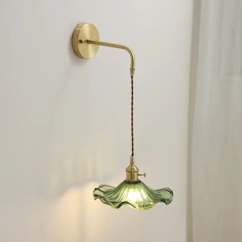 Decorbites amber glass wall sconce featuring a delicate green glass lamp with fluted petal design and brass hardware