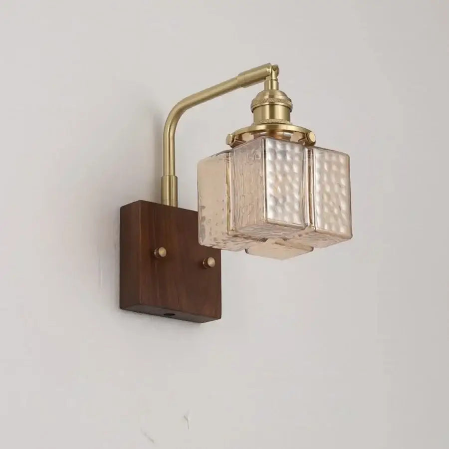 Decorbites amber glass led wall sconce with brass finish and walnut wood base mounted on dark wood background