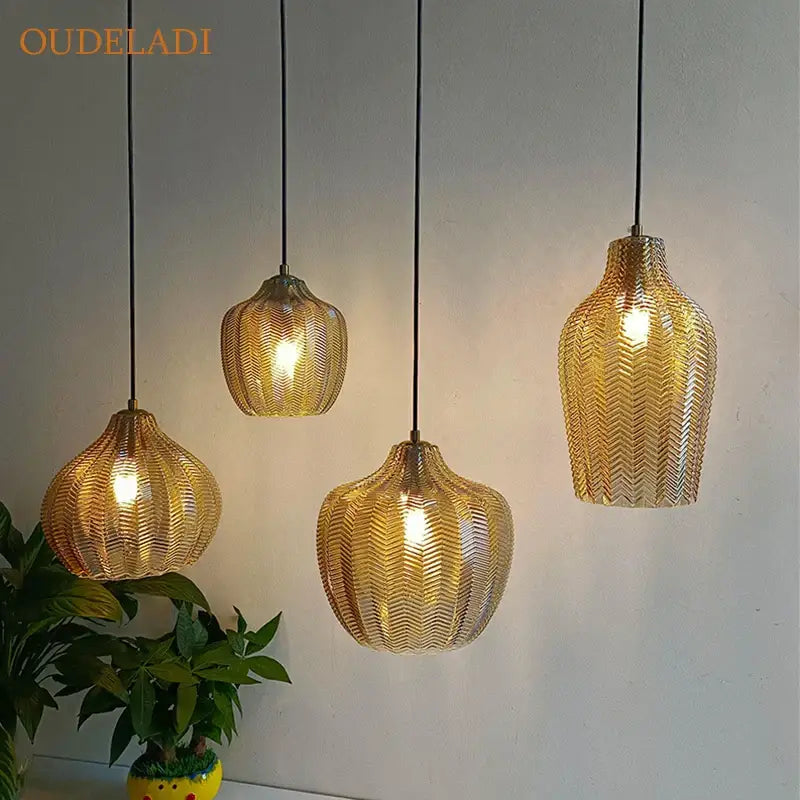 Gold-colored woven metal pendant lights with a chevron pattern from DecorBites amber glass pendant collection