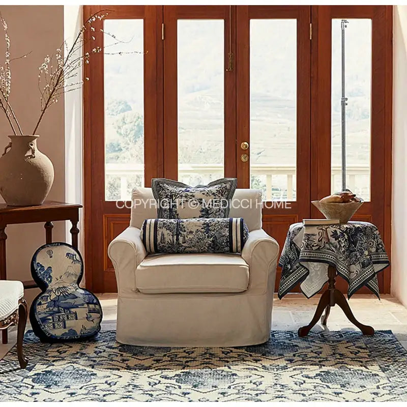 Cream-colored slipcovered armchair with rolled arms and indigo jungle decorative hand-painted cushion covers