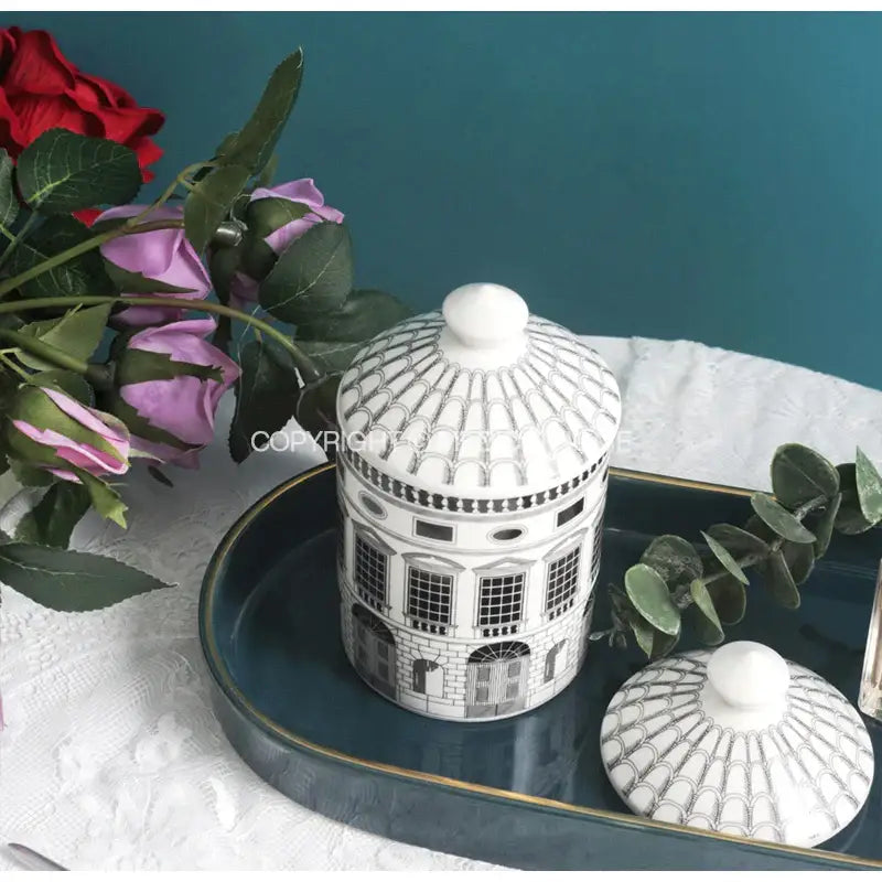 White ceramic candle jar with black architectural detailing and domed lid inspired by ancient roman architecture