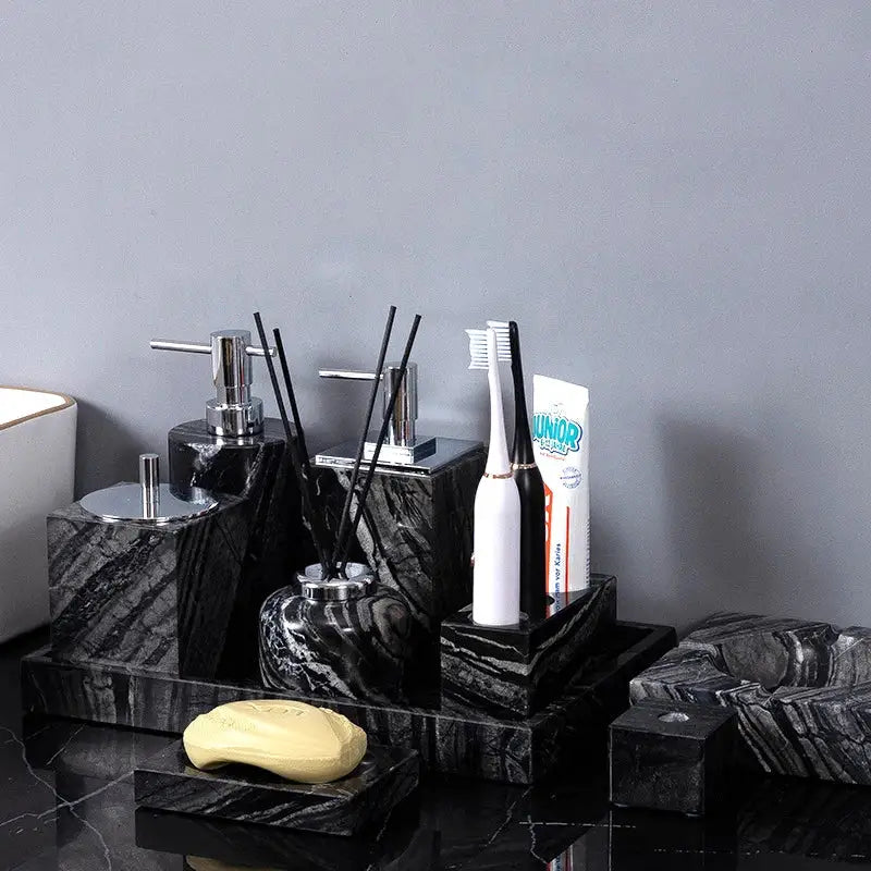 Black marble bathroom accessory set with sleek chrome dispensers featuring ancient wood grain design by DecorBites