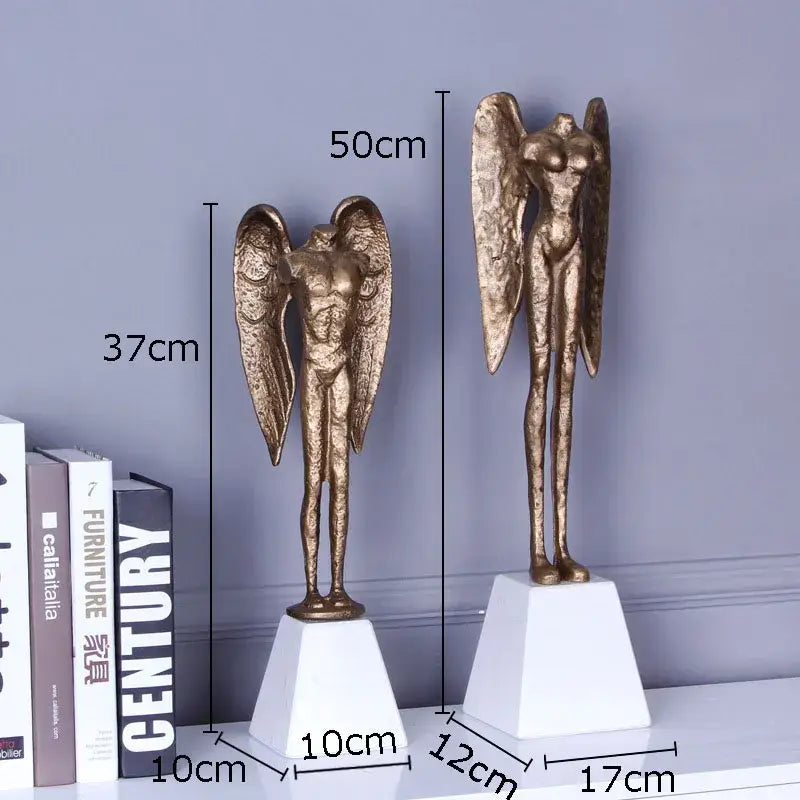 Two golden angel abstract figures sculpture cast iron home decor statues on white pedestals by DecorBites