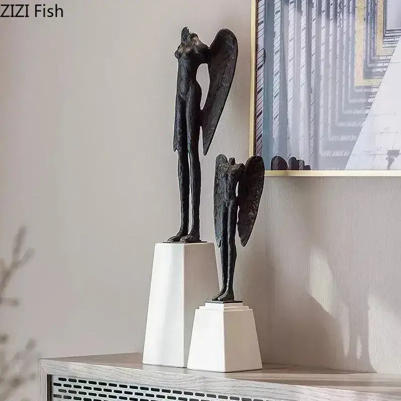 Two dark matte cast iron angel abstract figures sculpture with elongated limbs and detailed wings on white pedestals