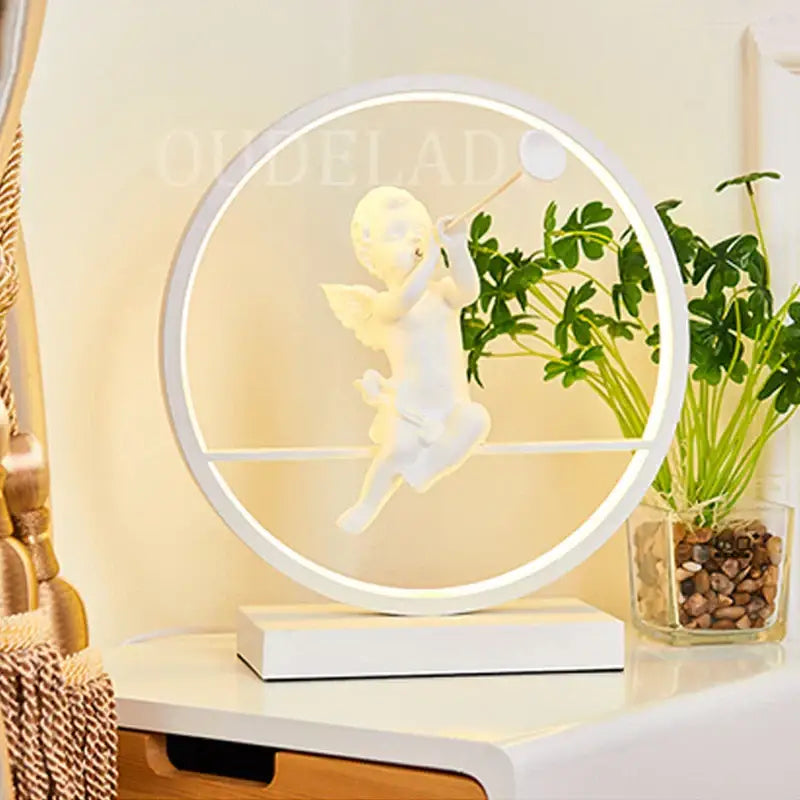 White circular led table lamp featuring a sculpted angel doll bird suspended within the glowing frame for home decor