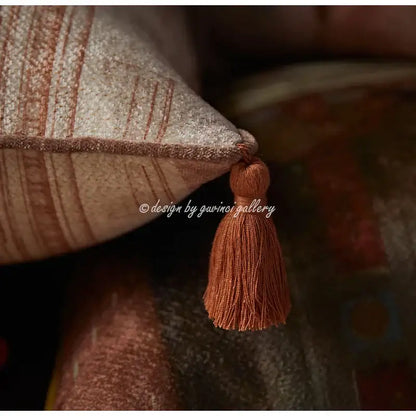 A warm terracotta tassel of fine threads hangs from the corner of a DecorBites™ angel eyes lumbar pillow cover
