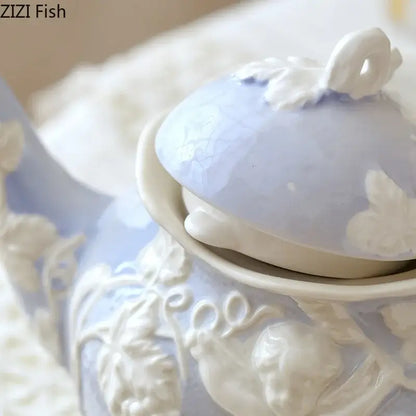 A delicate light blue ceramic teapot with intricate white angel figures relief and a matching lid from decorbites collection