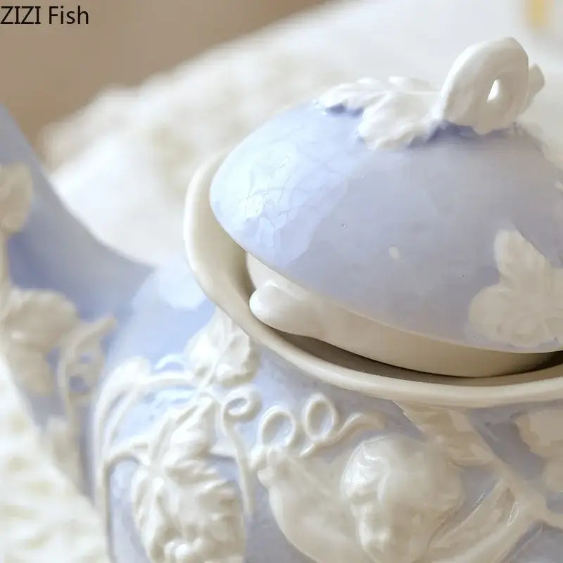 A delicate light blue ceramic teapot with intricate white angel figures relief and a matching lid from decorbites collection