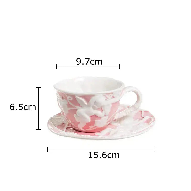 Pink ceramic teacup with white angel figures relief design resting on matching saucer from decorbites ceramic set
