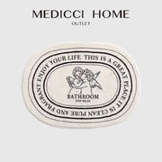 Cream-colored decorbites angel print shaggy bath rug 40x60cm with black embroidered cherubs and relaxing text design