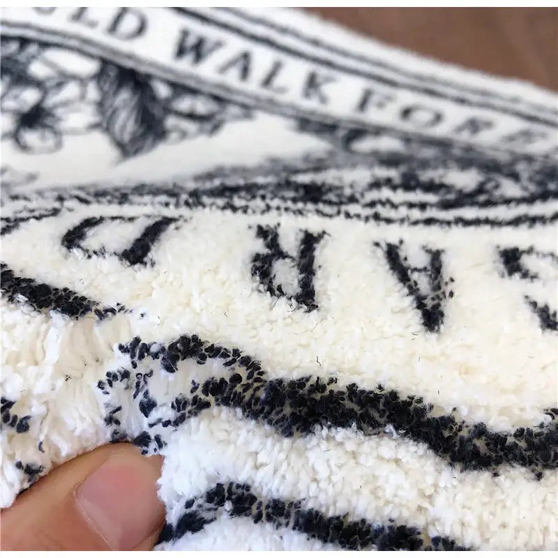 Cream-colored plush fleece bath rug with bold black embroidered angel print shaggy decorative patterns 40x60cm