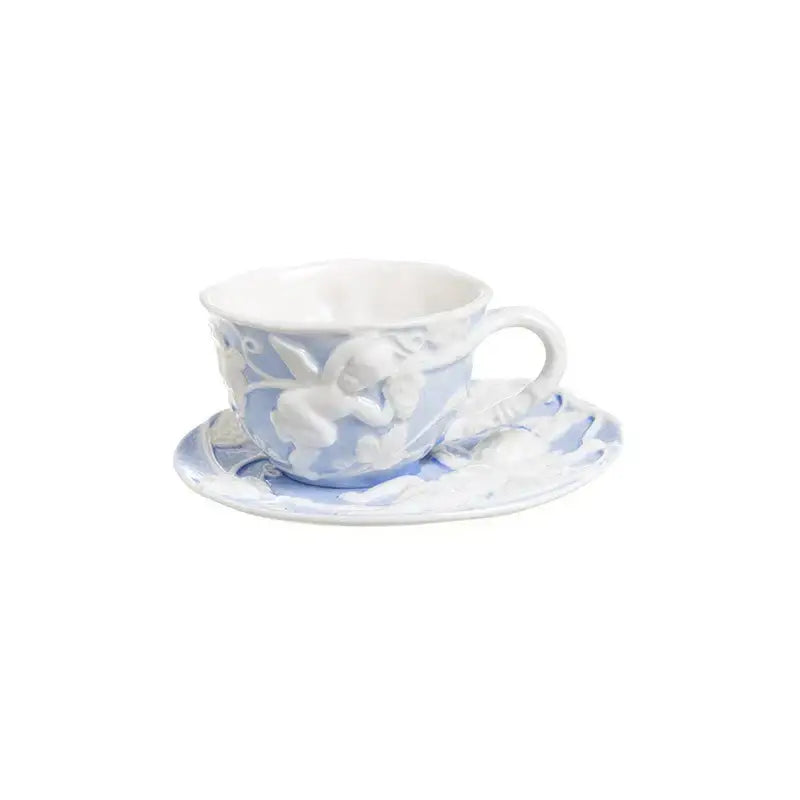 A delicate light blue angel relief ceramic teacup with white cherub design on its matching relief ceramic tableware set saucer