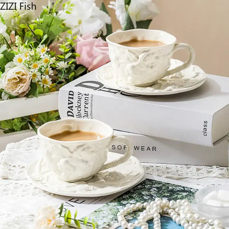 White ceramic coffee cups with intricate floral embossing and matching saucers from decorbites™ angel relief ceramic tableware set