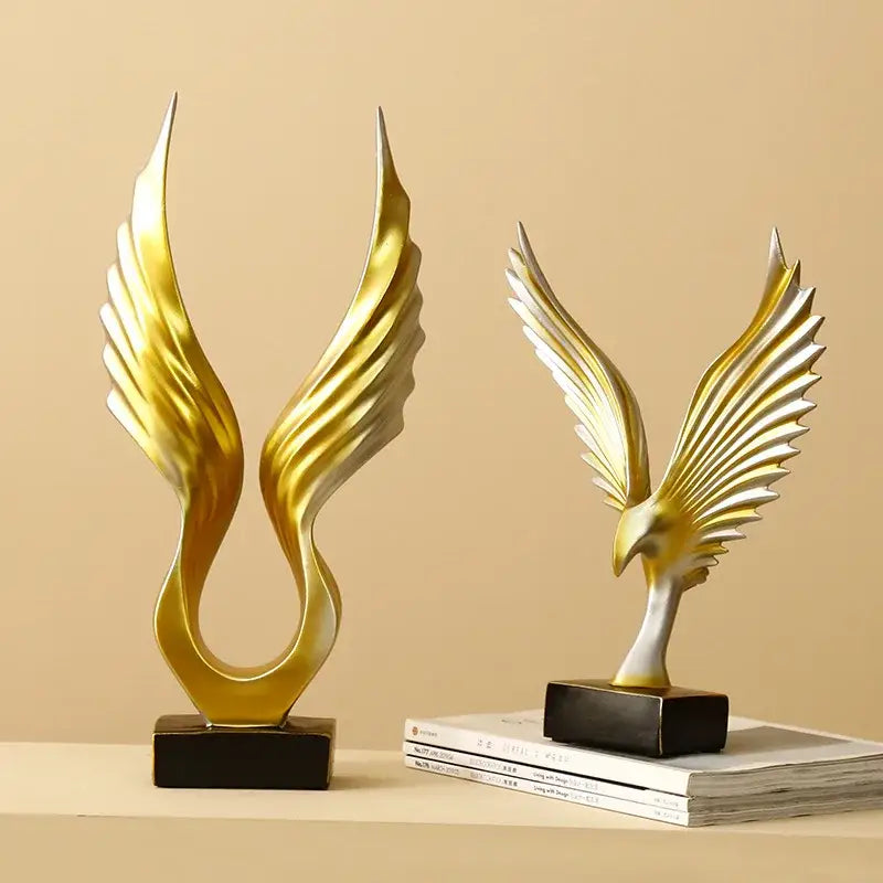 Golden and silver abstract angel wings sculpture in resin with sleek winged designs on black rectangular bases for decor