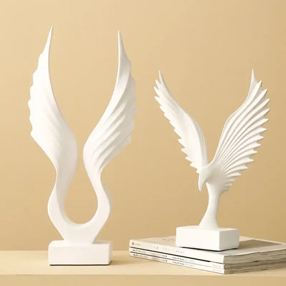 Two white ceramic bird sculptures featuring an angel wings sculpture and a detailed eagle wings sculpture in resin