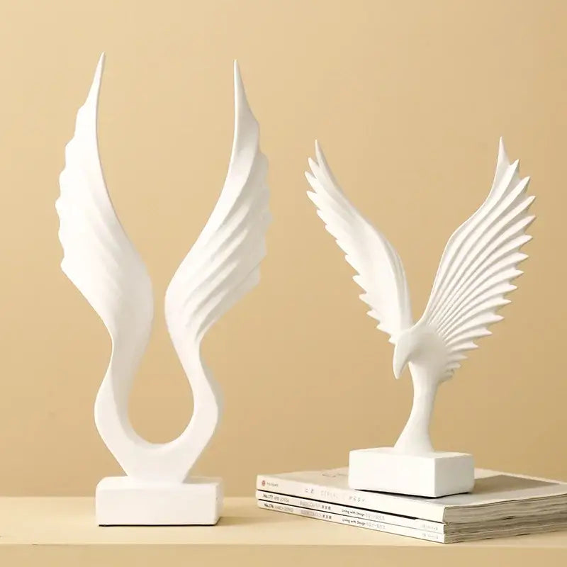 Two white ceramic bird sculptures featuring an angel wings sculpture and a detailed eagle wings sculpture in resin