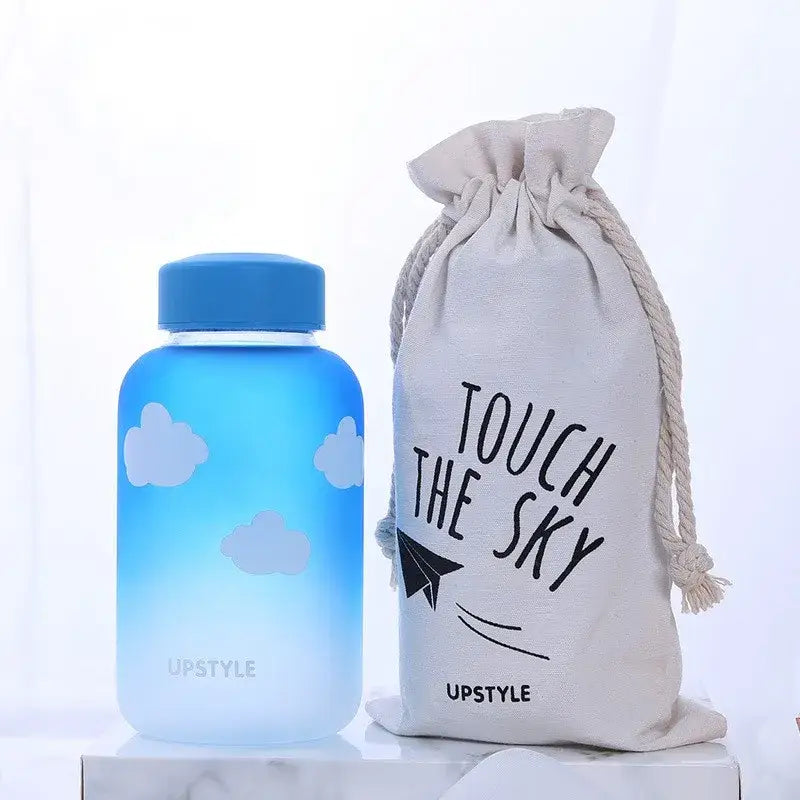 Blue gradient glass water bottle with white cloud decals and a matching blue lid by DecorBites for outdoor use