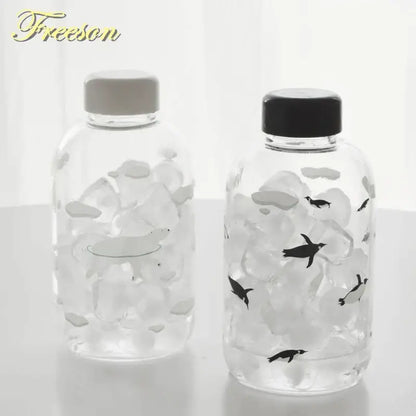 DecorBites™ animal glass water bottle with clear body, penguin design, black and gray caps for outdoor use