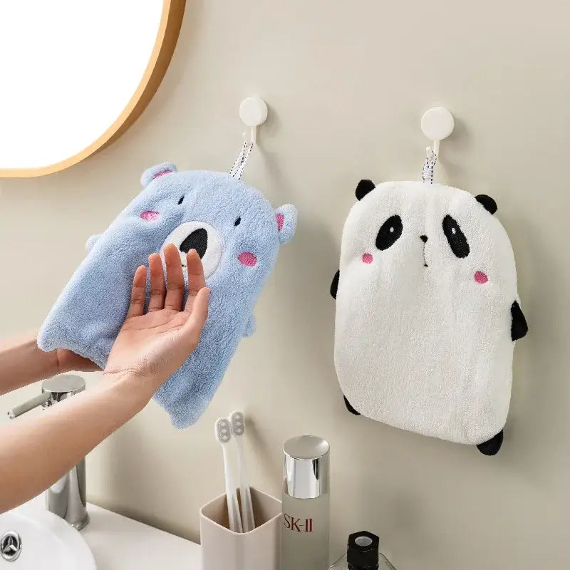 Blue plush bear-shaped bath sponge with pink cheeks hanging beside a white panda animal hand towel from decorbites hand towels set