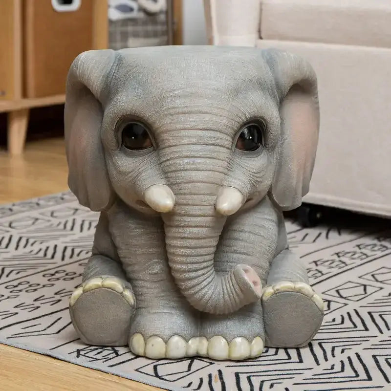 Gray resin baby elephant figurine with oversized ears glossy black eyes and ivory tusks as a resin sculpture footstool seat