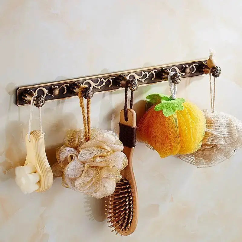 Antique brass towel rack with ornate scrollwork designed as part of decorbites bath hardware and toilet brush holder set